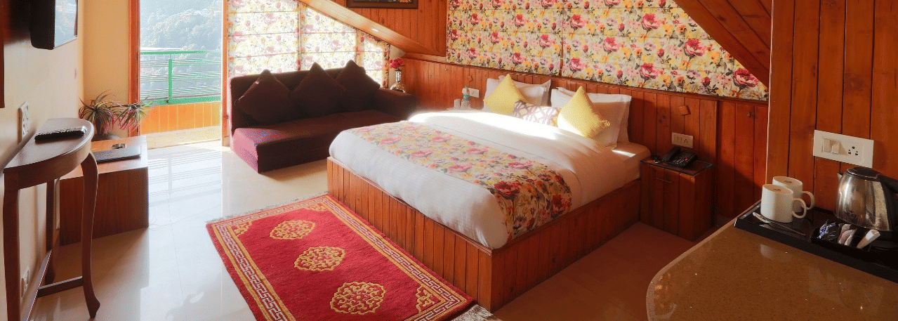 A full view of a cottage-styled bedroom with wooden ceiling and glass windows | Mongas Hotel & Resort, Dalhousie