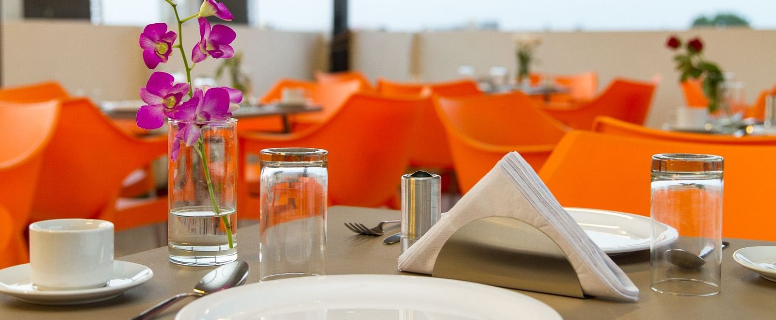 An outdoor table setting with orange napkins and glassware at Sanctum Suites Whitefield, Bangalore.