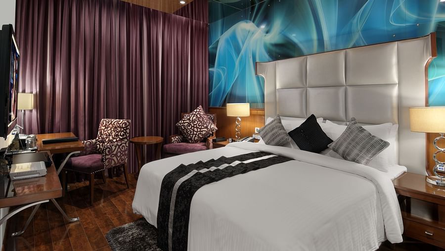 A room with a large bed and teal accents and a work desk at The Elanza Hotel.