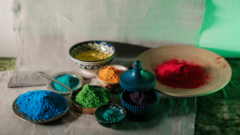 Multiple bowls filled with coloured powder placed on a surface, commonly used during festival celebrations.