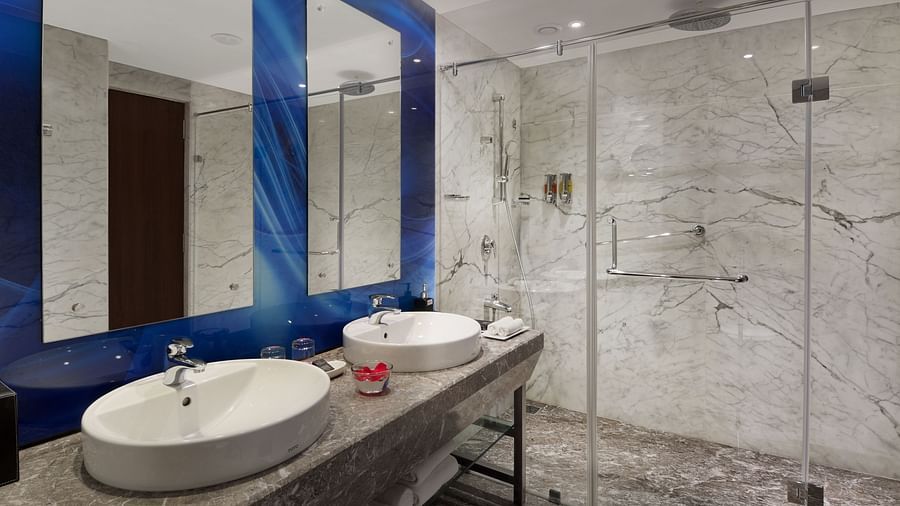 Modern bathroom with double vanity and glass-enclosed shower at The Elanza Hotel.