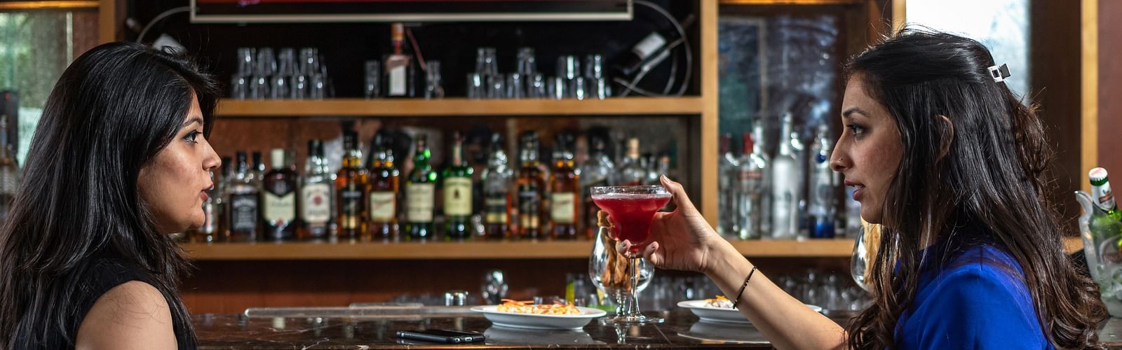 Two people enjoying the drinks in the bar at Golden Suites, Gurgaon