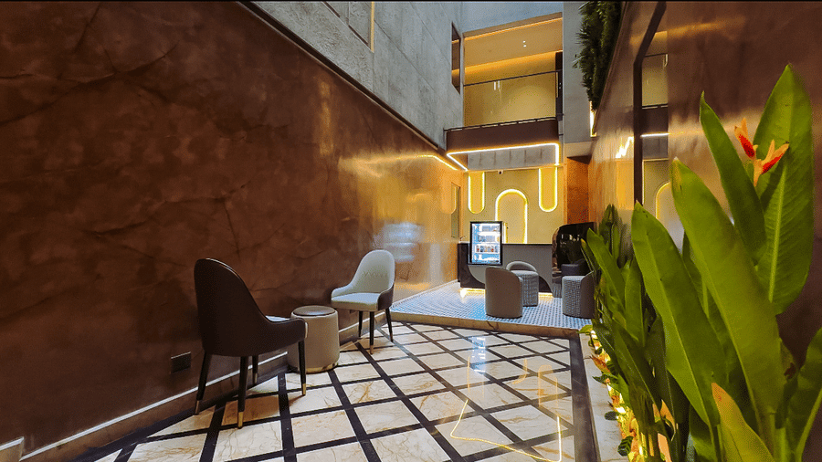 The lobby of F Hotels, Bengaluru, featuring a criss-cross patterned marble flooring, leading the the brightly lit cafe area.