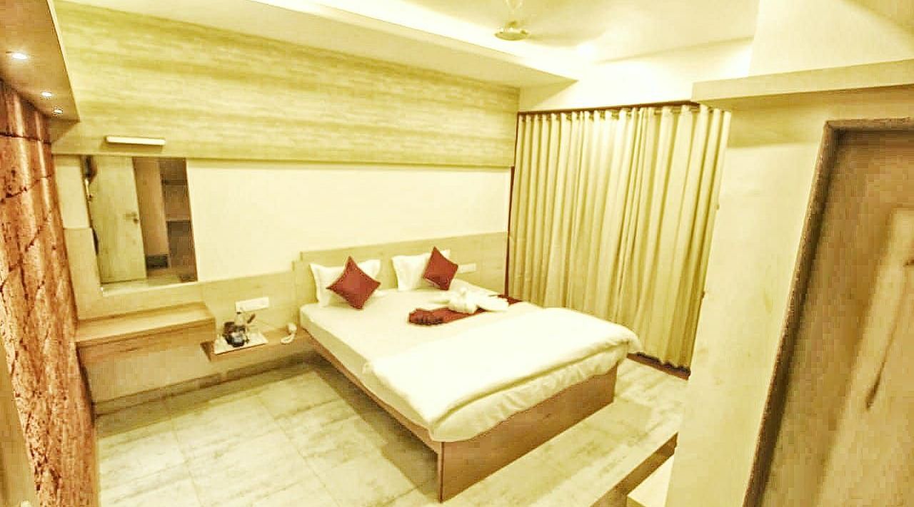 A spacious room with a large bed and windows beside it, covered with curtains. There is a wall-mounted mirror at SeaFort Beach Resort
