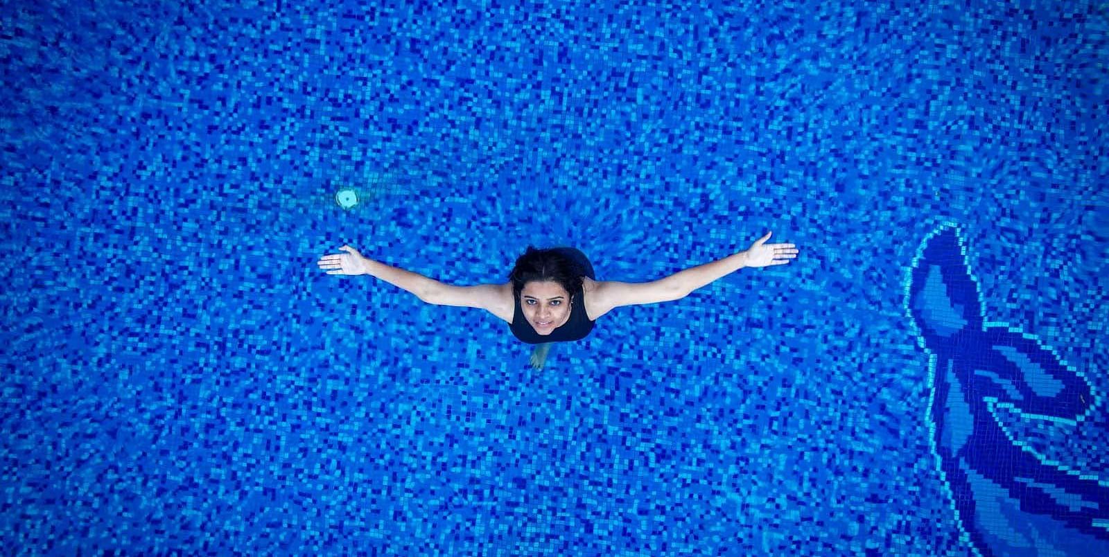 Top view of a girl with her hands spread out at the outdoor swimming pool in Coorg Jungle Camp Backwater Resort in Kushalnagar.