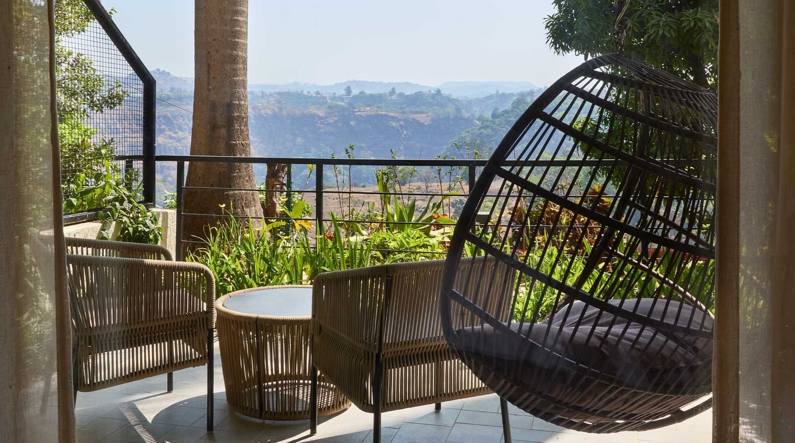 A beautiful veranda with a swing and chairs overlooking beautiful mountain views at Athiva Resorts & Spa, Khandala | Nature resorts near Khandala are ideal for weekend trips