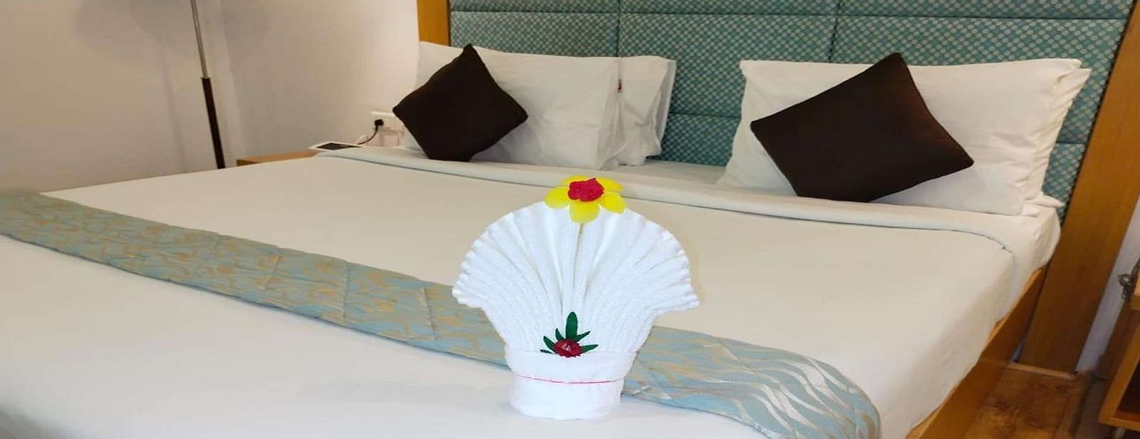 Close up of a Executive Suite at Dhanalakshmi Srinivasan Hotels, Perambalur featuring a bed with white linens and towel on it.