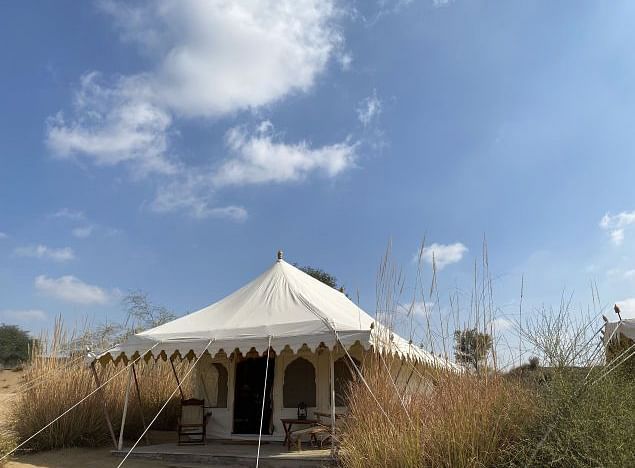 A facade image of a tent on a bright sunny day in the desert area with spare vegetation - MANVAR Resort & Desert Camp