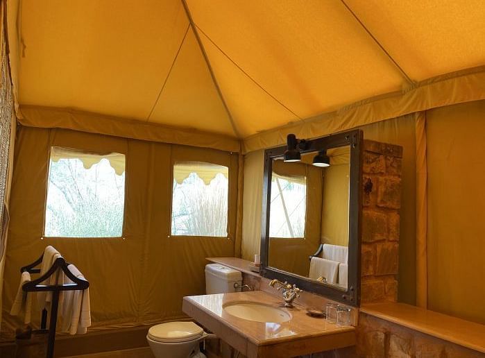 An image of the washroom area inside a tent with toiletries, wash basin and a mirror - MANVAR Resort & Desert Camp
