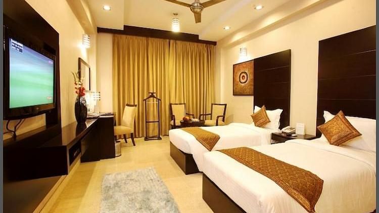 A room featuring twin beds, a TV, sofa chairs and a vanity section - Five Elements Hotels