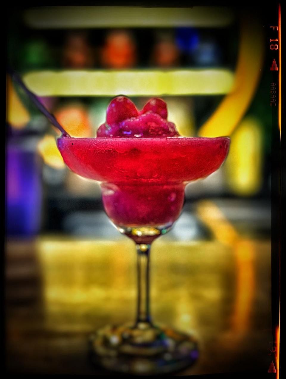 A vibrant drink in a stemmed glass, against a softly blurred background at Cenneys Gateway.
