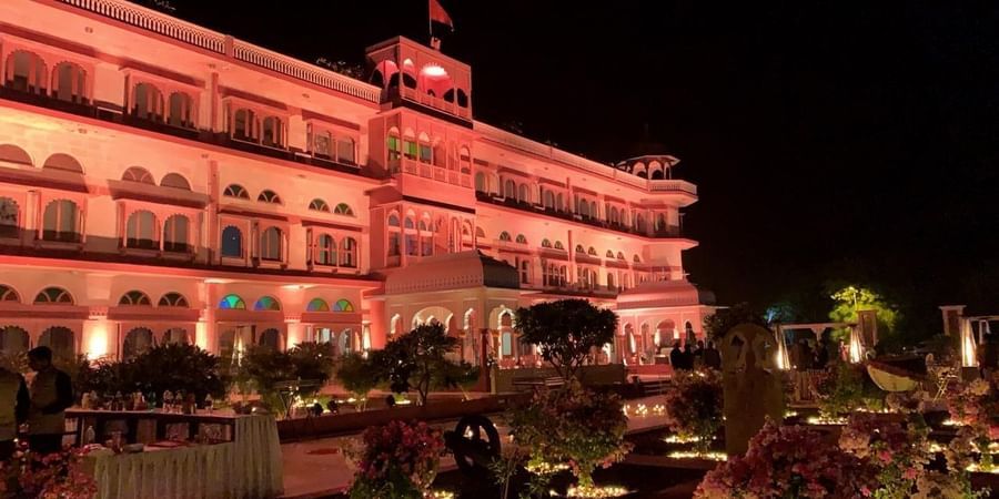 Front Facade of  Umaid Palace Dausa featuring a stretched and multi storey building lit with red light at night for an event.