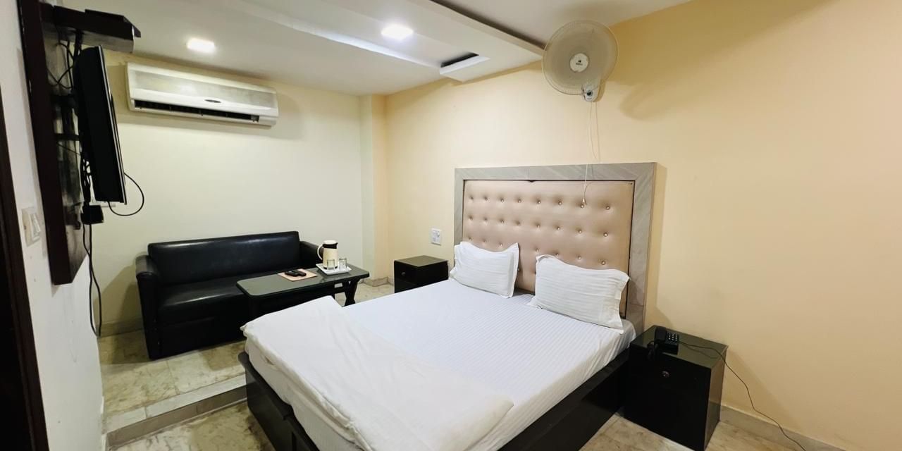 A cozy deluxe room featuring a comfortable bed with white linens and a light-colored headboard, perfect for a restful stay. | Deluxe Room | Ajay Guest House