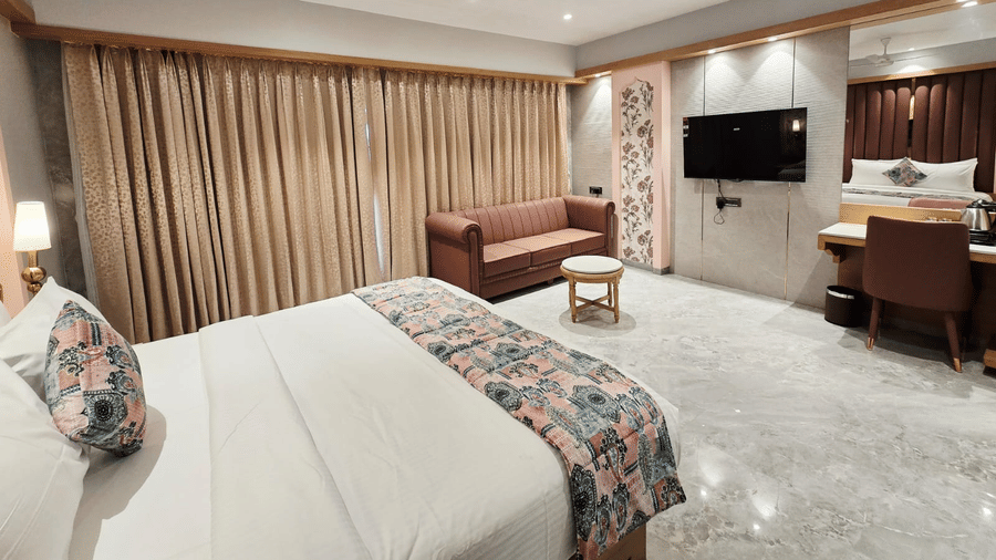 Spacious suite with bed, seating area, and TV at Hotel Mumbai House, Digha, Airoli.
