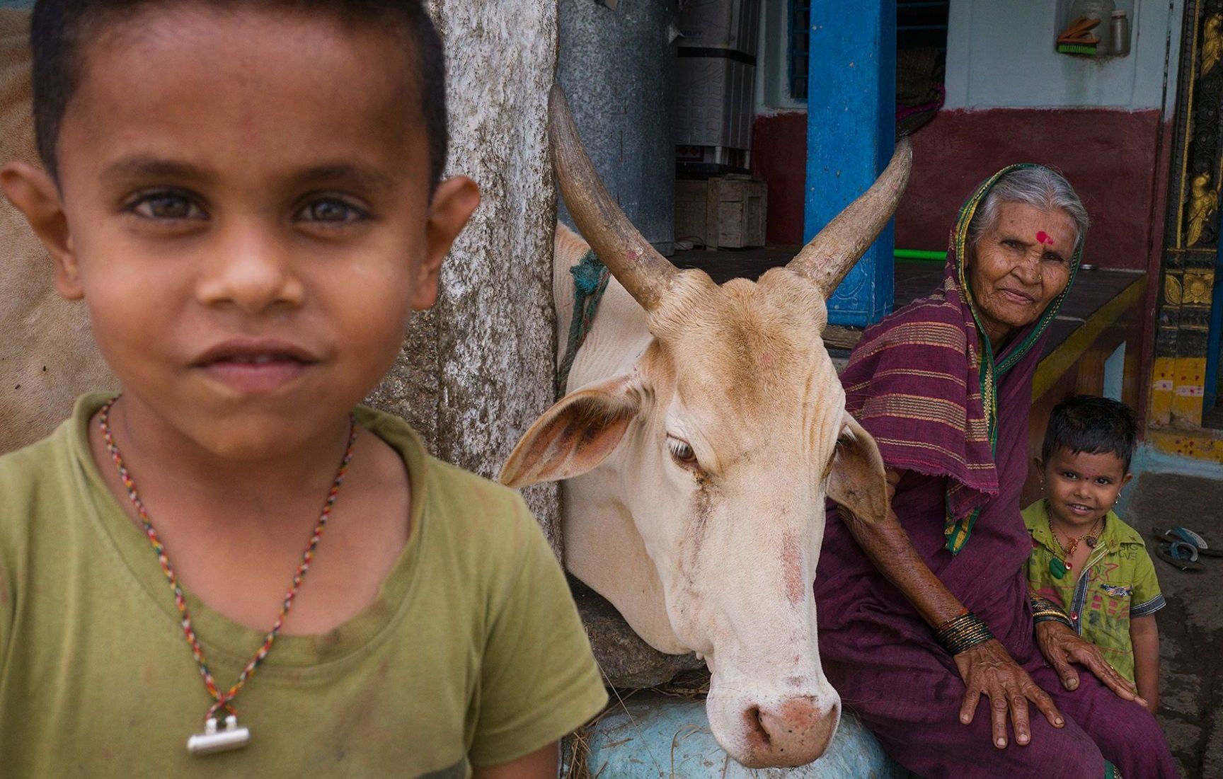 Rural Indian scene with a child, woman, and cow.