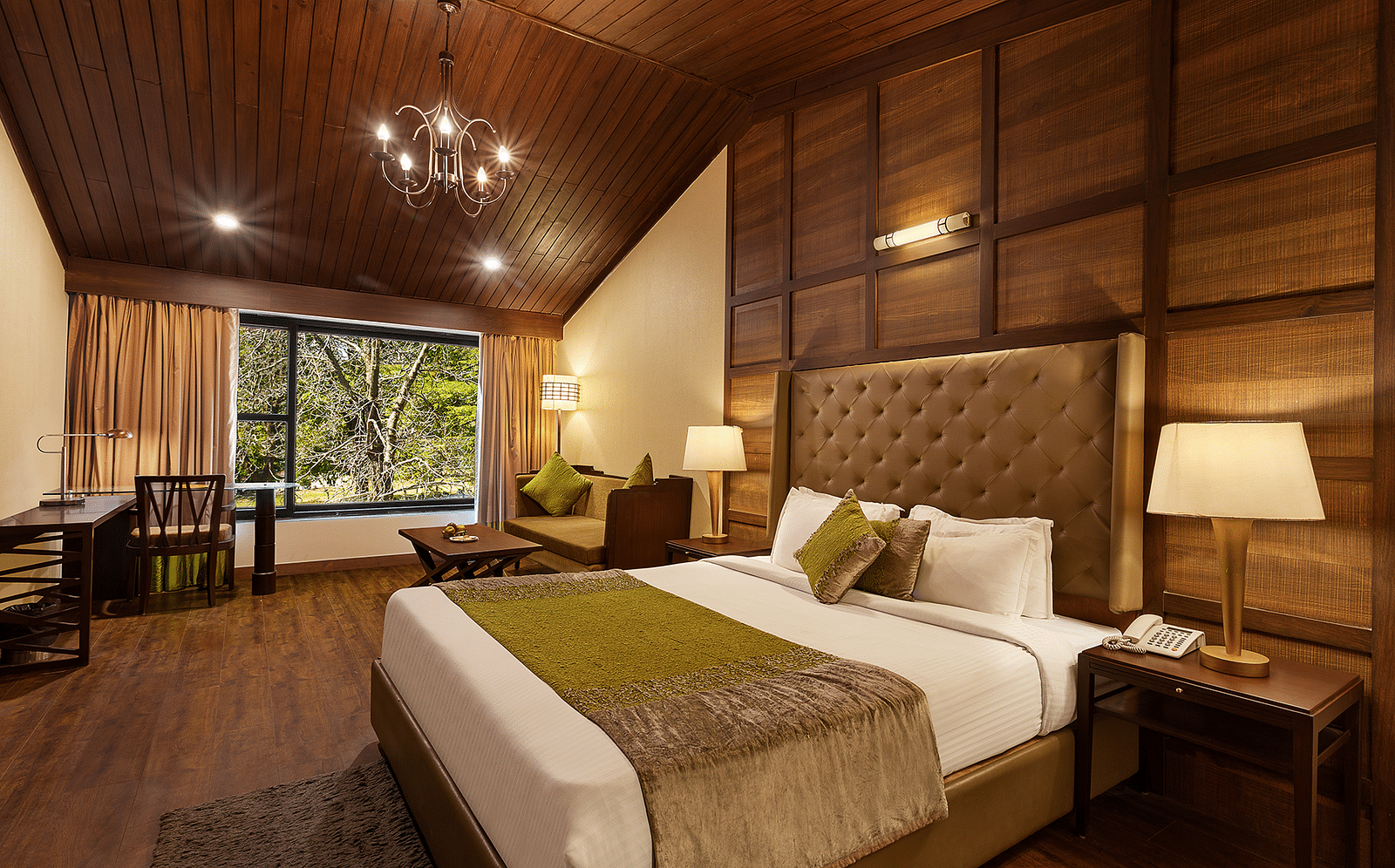 A bedroom with a large bed and a workdesk and chairs on the corner of the room, with large windows with trees visible - The Earl's Court, Nainital