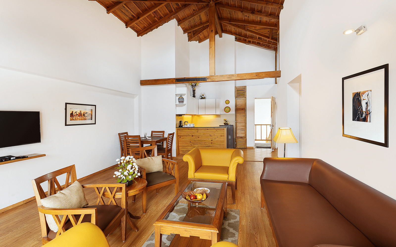 Living room with comfortable sofa and chair with attached kitchenette of Two Bedroom Apartment - The Pinewood Nainital