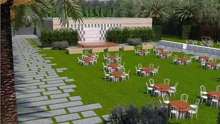A wide view of lawn with stage, tables, and chairs on grass, stone pathways on either side, and palm trees around the area at Merlis Hotel, Coimbatore
