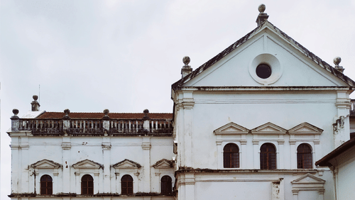 Facade image of Se Cathedral church with a garden in front of it and white clouds in the background