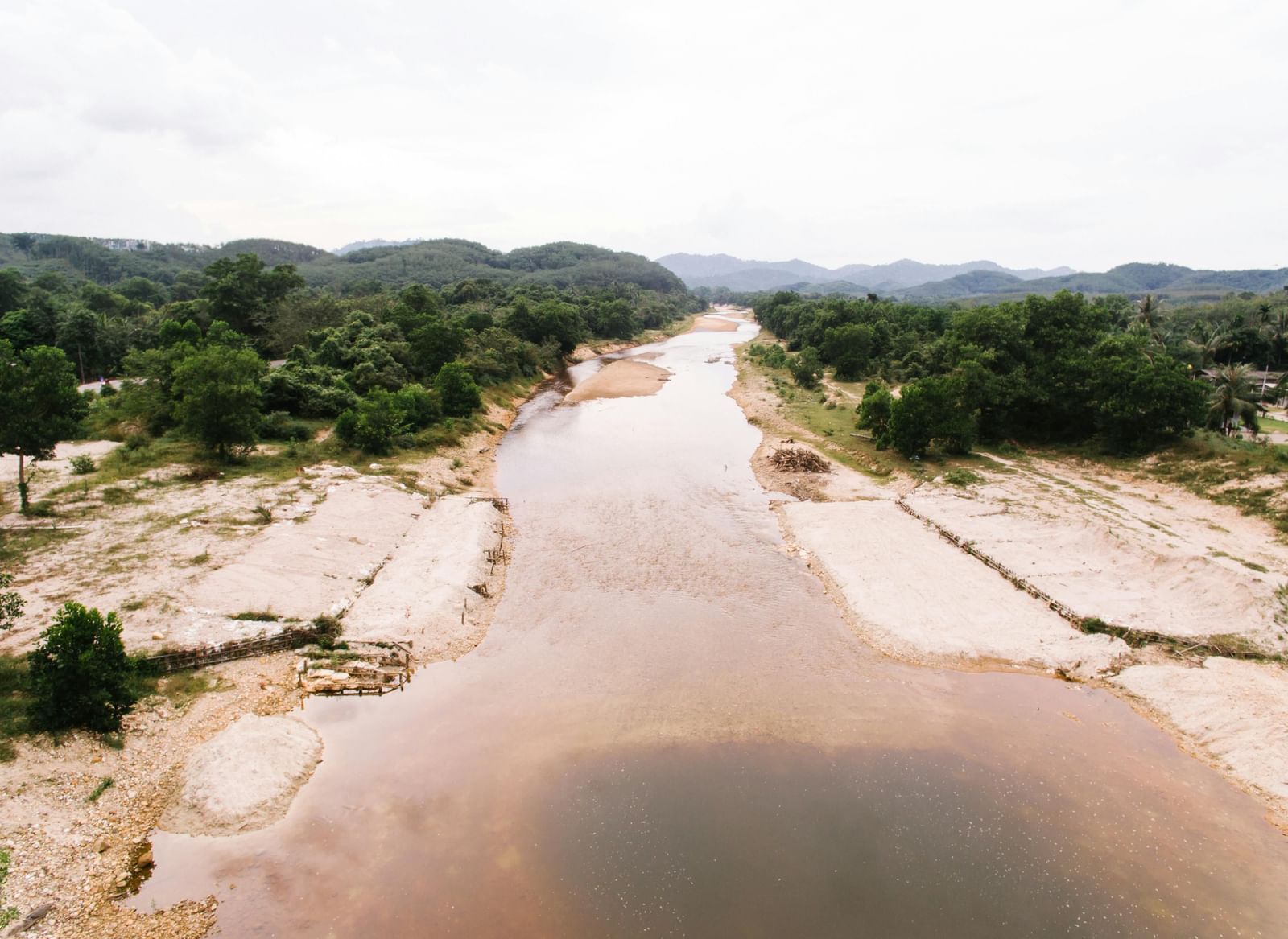 An aerial view of a wide, meandering river with sandy banks, cutting through a valley.