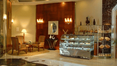 Elegant and cosy Chai Bar at The Manohar, Hyderabad, showcasing a bakery display, plush corner seating, and warm ambient lighting with floor lamps