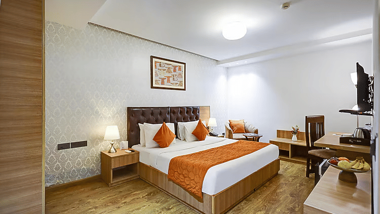 A well-lit guest room showing a double bed, a dedicated wooden study desk with a chair, and large windows - Hotel 91 HUDA City Centre, Gurugram