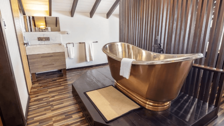 A luxurious copper-colored freestanding bathtub is featured in a spacious, elegantly designed bathroom with wooden accents.