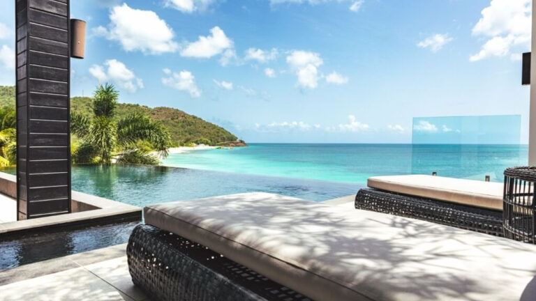 An outdoor lounge area with comfortable seating offers panoramic views of the ocean and a distant shoreline.