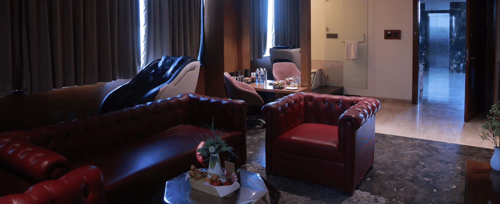 Sky Suite living area with tufted red leather sofas, a massage chair and a work desk