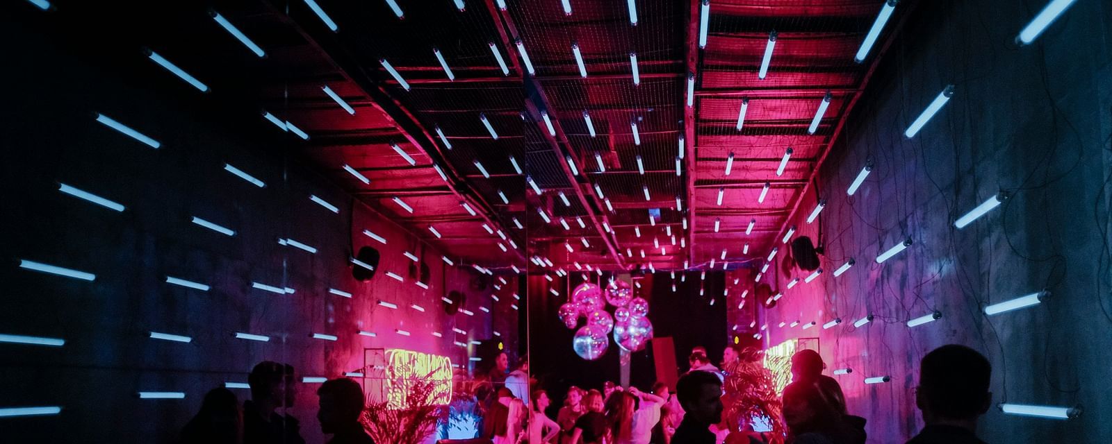 An overview of a night club with red light and people waiting in line