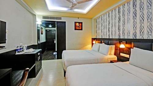 Deluxe Room at Pride Ananya Resort Puri featuring a double bed with a single bed next to it in front of a TV mounted on the wall
