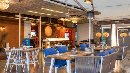 Spacious dining zone at the Nazaara Restaurant, Papaya Tree Hotels, featuring modern tables and chairs arranged for guests in a bright, open setting.