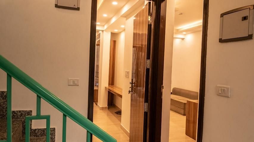 A hallway with staircase railing painted green, leading to rooms on the upper and lower levels.