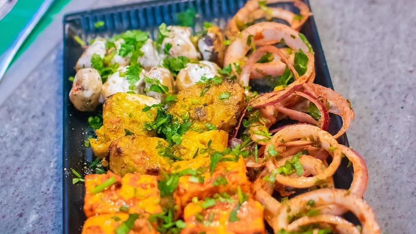 An image of a food platter where various food items are placed and garnished with leaves, sauce, and lettuce is placed at Themis Barbecue House, NSP Pitampura