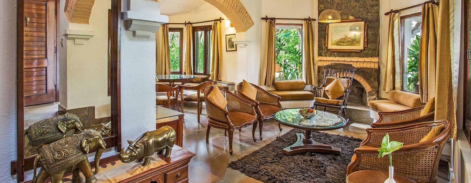 An image of a living area with many valuable and decorative items kept at top of the cabinet and near that there is a wooden sofa set - The Riverview Retreat, Corbett