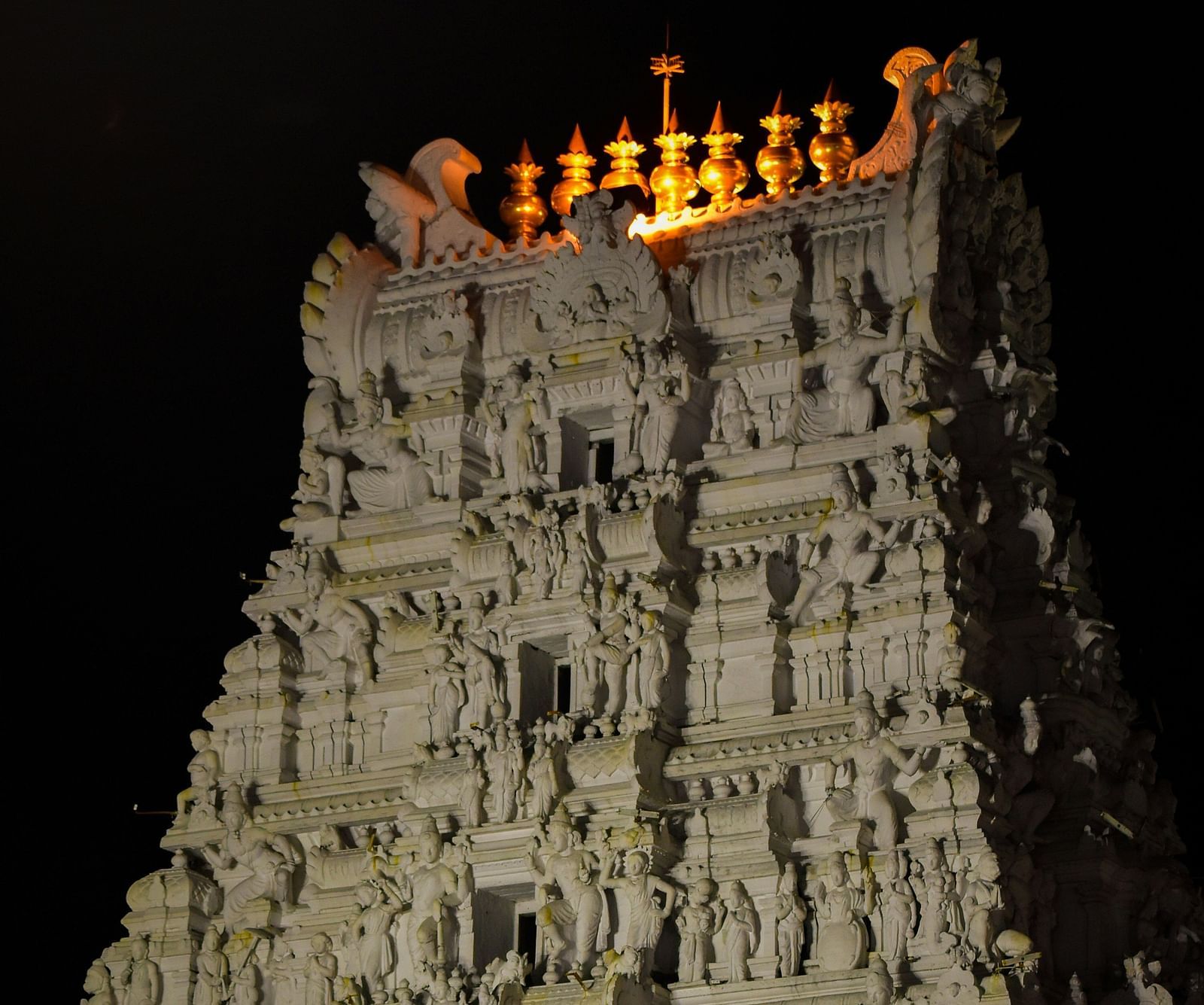 An overview of the facade of a temple in Tirupati with lights shining on it