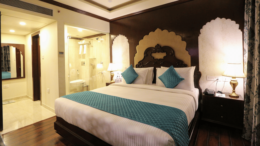 A bedroom at Comfort Inn Sapphire by Eastlynn Collections, Jaipur with queen size bed, arch design, side tables, and lighting.