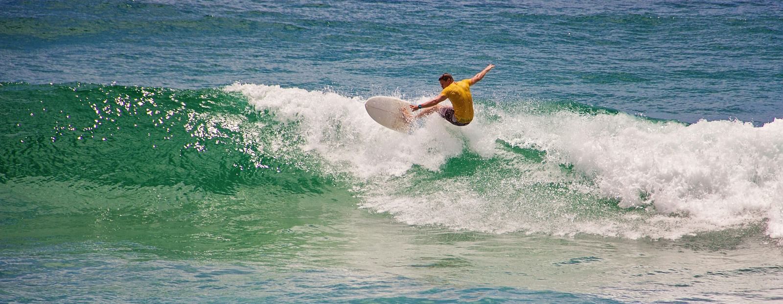 Man in yellow shirt surfing.