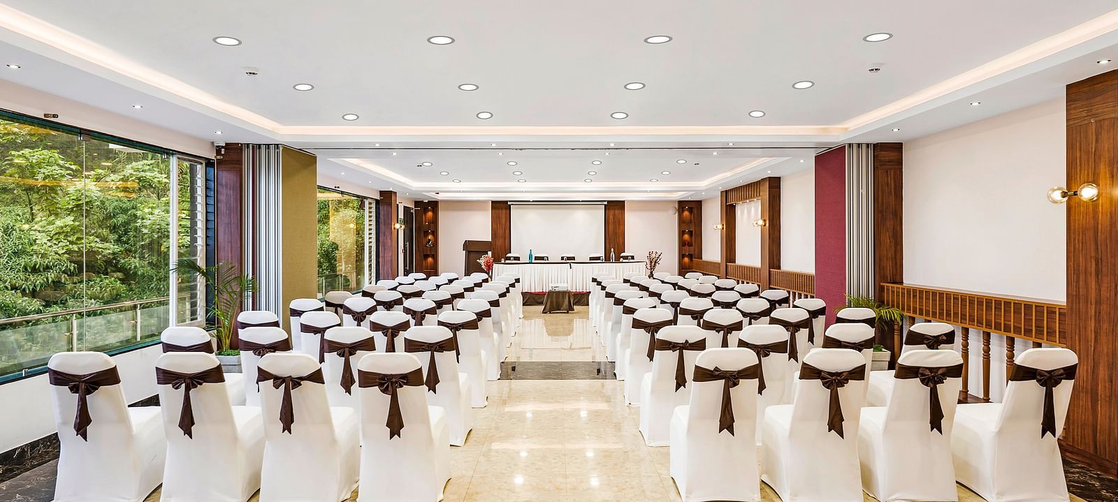 An image of a banquet space which is brightly lit with seating arrangement - GReaT Trails Kodaikanal By GRT Hotels