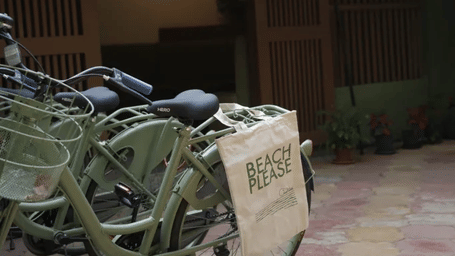 Bicycles are parked on a paved pathway beneath a white flowering bush at Oceanature Resort, Alibaug.