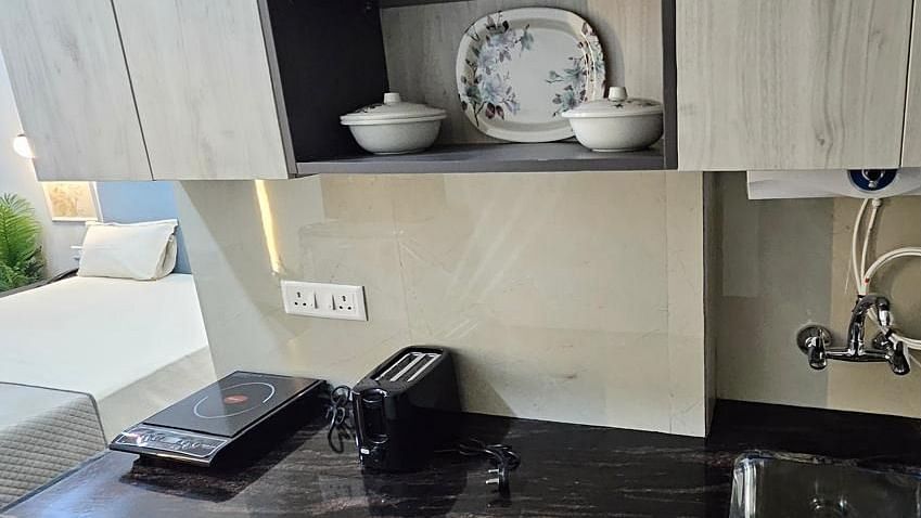 A low-angle view of the cupboard and a shelf with neatly arranged plates and cups at Urban Suites by BluSalzz, Jaipur.