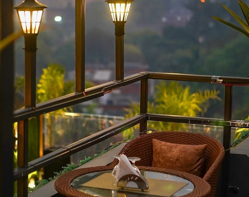 Two chairs facing each other on a terrace with warm lights beside it on a late evening.