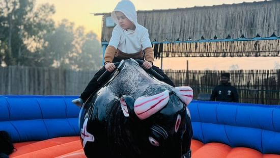 A person riding on a mechanical plastic bull at Themis Mudhouse - A Nature's Retreat Resort & Wellness