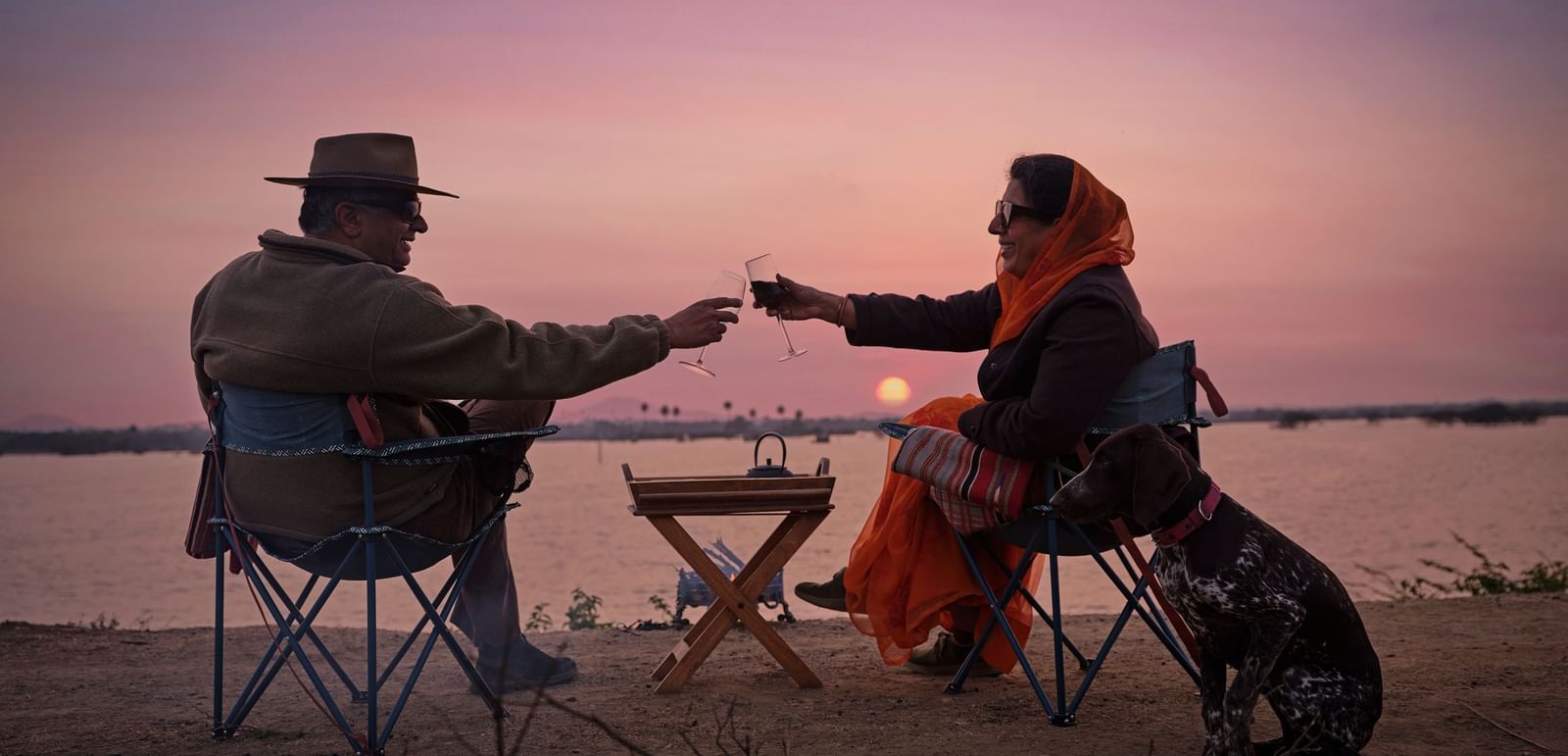image of a couple enjoying the sunset as they cling wine glasses at Dev Shree, Deogarh