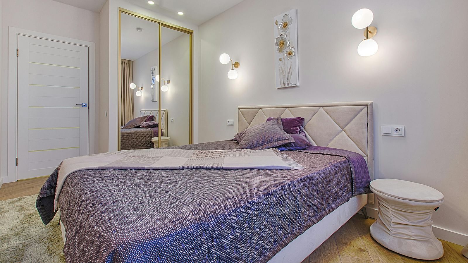 A bedroom with a king size bed with bright lighting and a round bed side table
