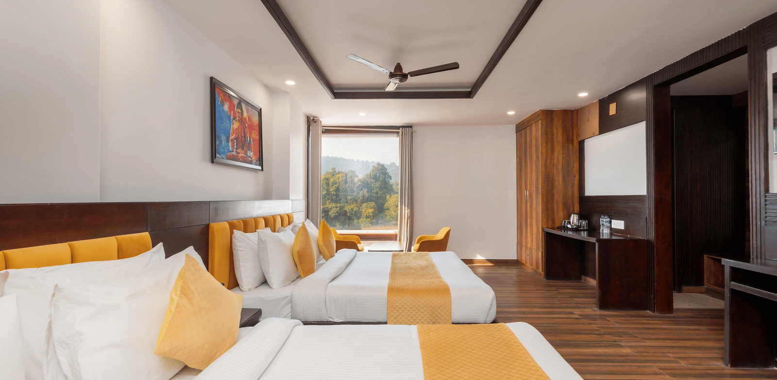 Interior of a room with 2 beds, a television, wardrobe area, and a window with outside view at Perfectstayz Premium Shanti Heritage, Haridwar.