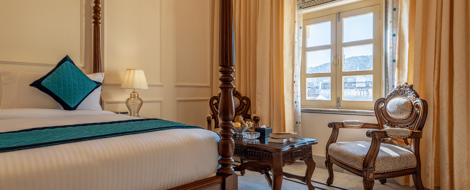 a bedroom with intricate paintings on the wall over the window with a common seating area in front of it - Brij Castle, Jaipur