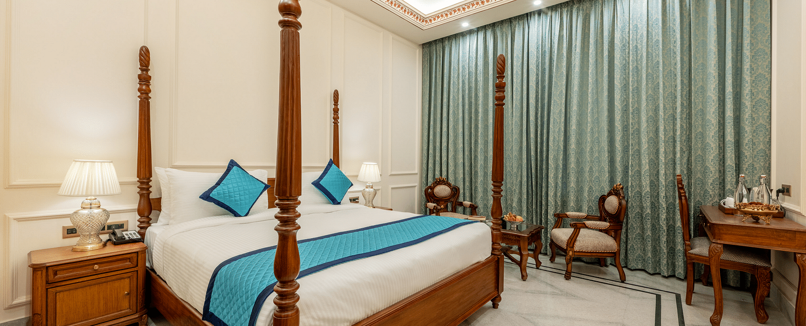 full view image of the room featuring a double bed along with a common seating area at the far end of the room - Brij Castle, Jaipur