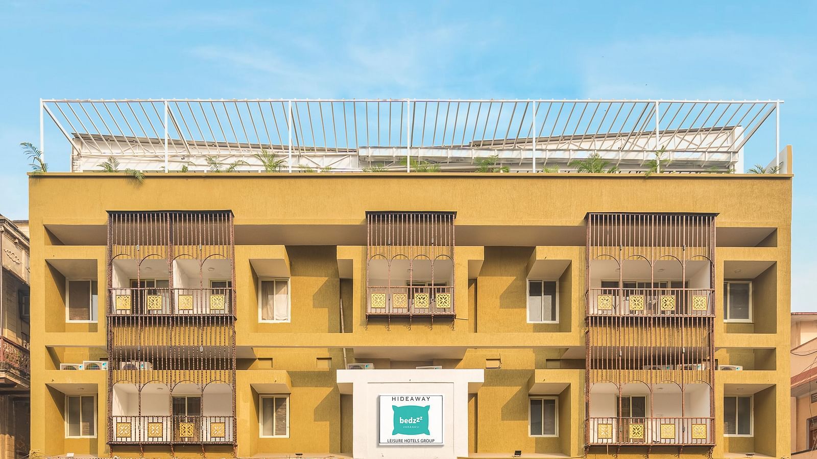 A close image of the front view of Bedzzz Varanasi, captured in daylight, featuring the logo of the property and the roof top area.