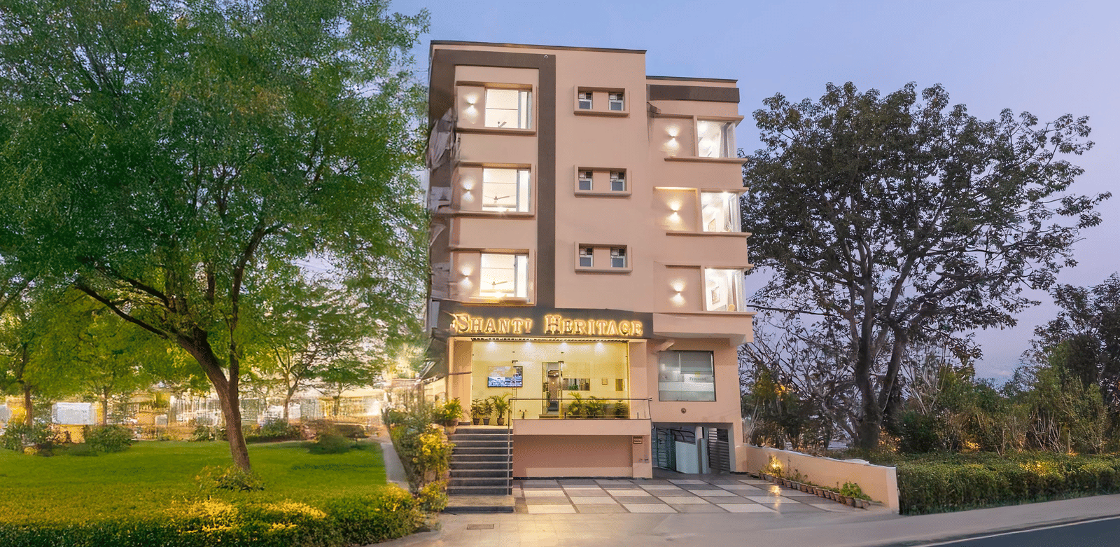 Facade of Perfectstayz Premium Shanti Heritage, Haridwar with trees surrounding the hotel.